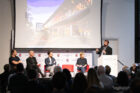 Speaker with 4 other panelists onstage during a presentation.