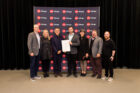 Award recipients stand backstage with award certificate in front of AIA Chicago backdrop