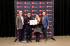 Award recipients stand backstage with award certificate in front of AIA Chicago backdrop